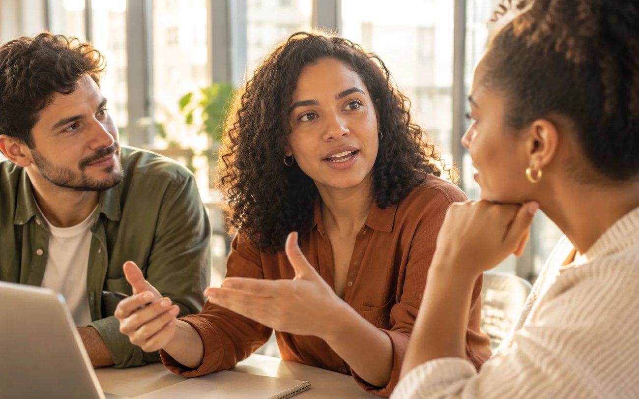 Roda de conversa numa sala clara, com uma pessoa expondo o ponto e duas escutando